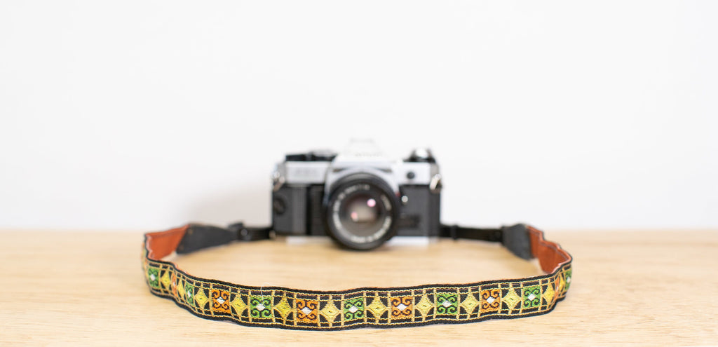 camera strap in shades of green, orange, and yellow.